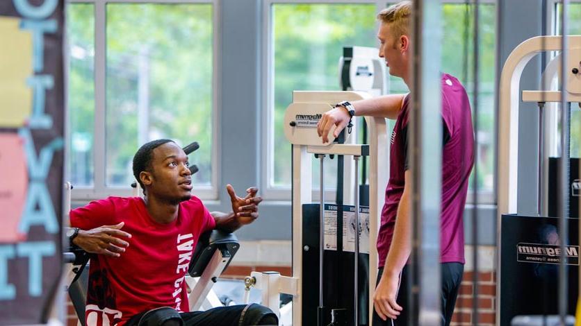 Two students talking while working out in fitness center